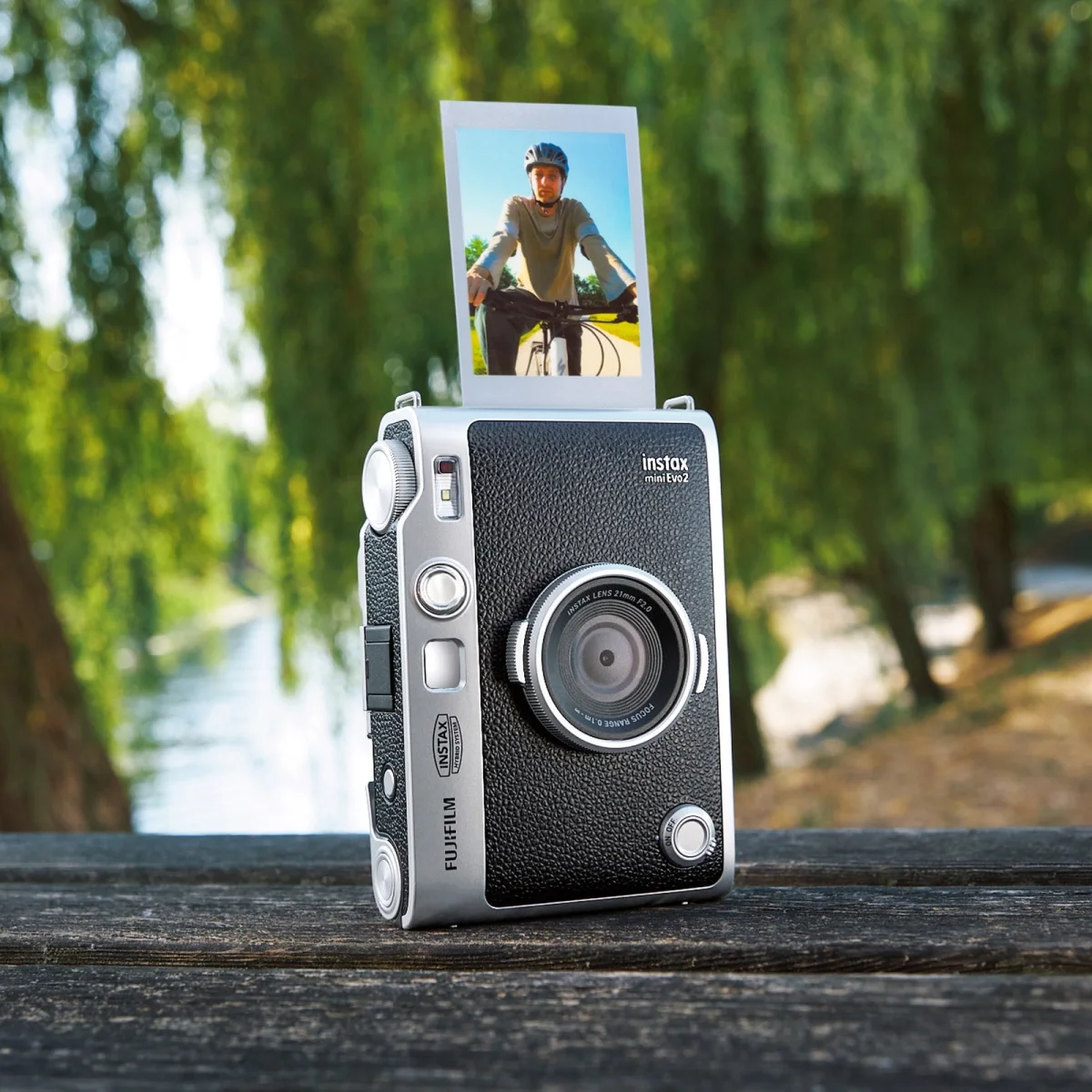 Fujifilm Instax mini Evo 2 hybrid instant camera with a printed photo showing a bicycle rider protruding from the top.