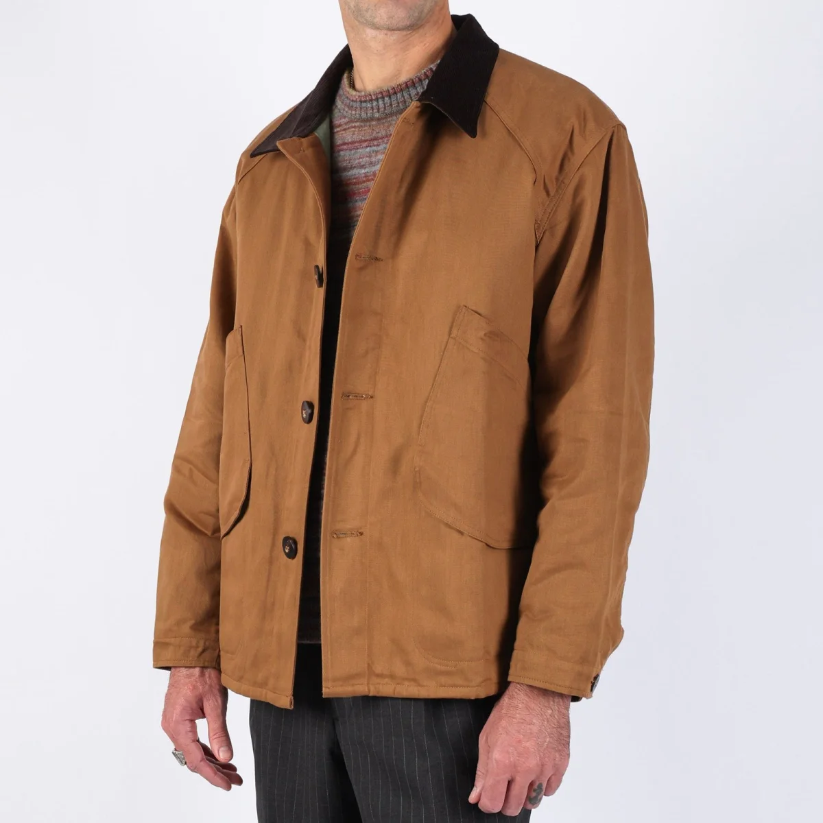 Brown canvas chore coat with a dark corduroy collar and button-front closure.