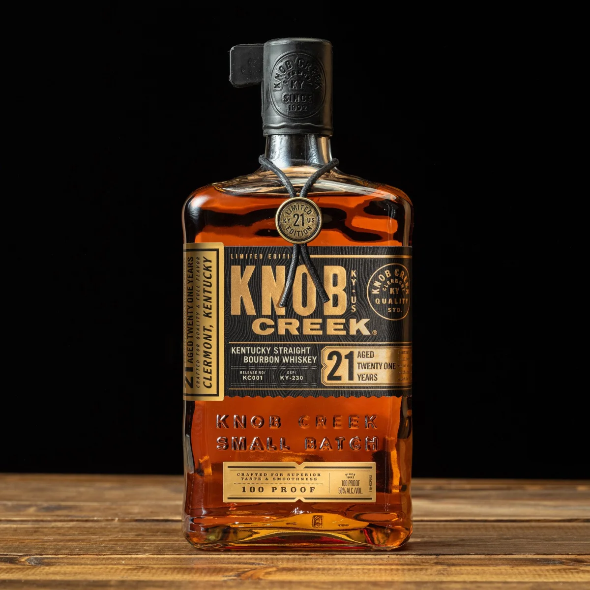 Knob Creek 21-Year-Old Kentucky Straight Bourbon Whiskey bottle featuring a gold label, wax-sealed cap, and a leather neck tag.