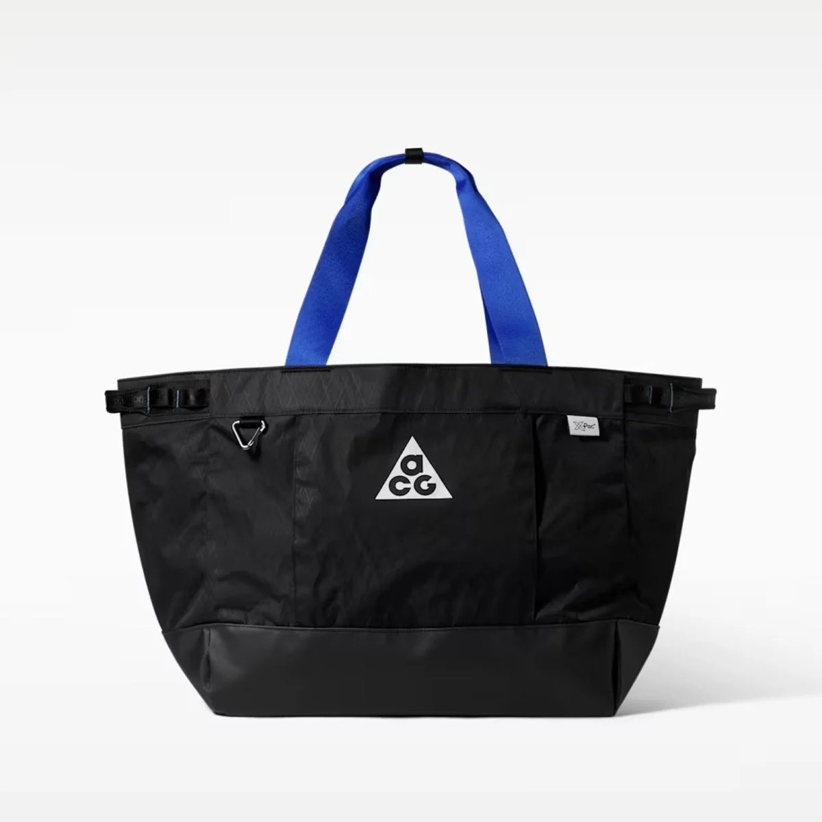 Black tote bag with a blue handle, white ACG logo on the front, and a small rectangular label on the upper right, shown against a plain white background.
