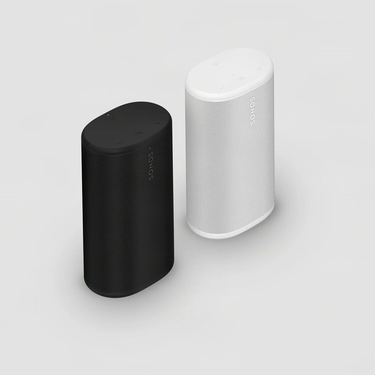 Two Sonos wireless speakers, one black and one white, standing upright on a light gray surface.