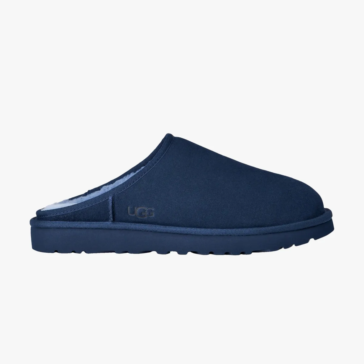 Navy blue slip-on suede slipper with a fuzzy interior, flat sole, and the UGG logo embossed on the side, shown in a side view.