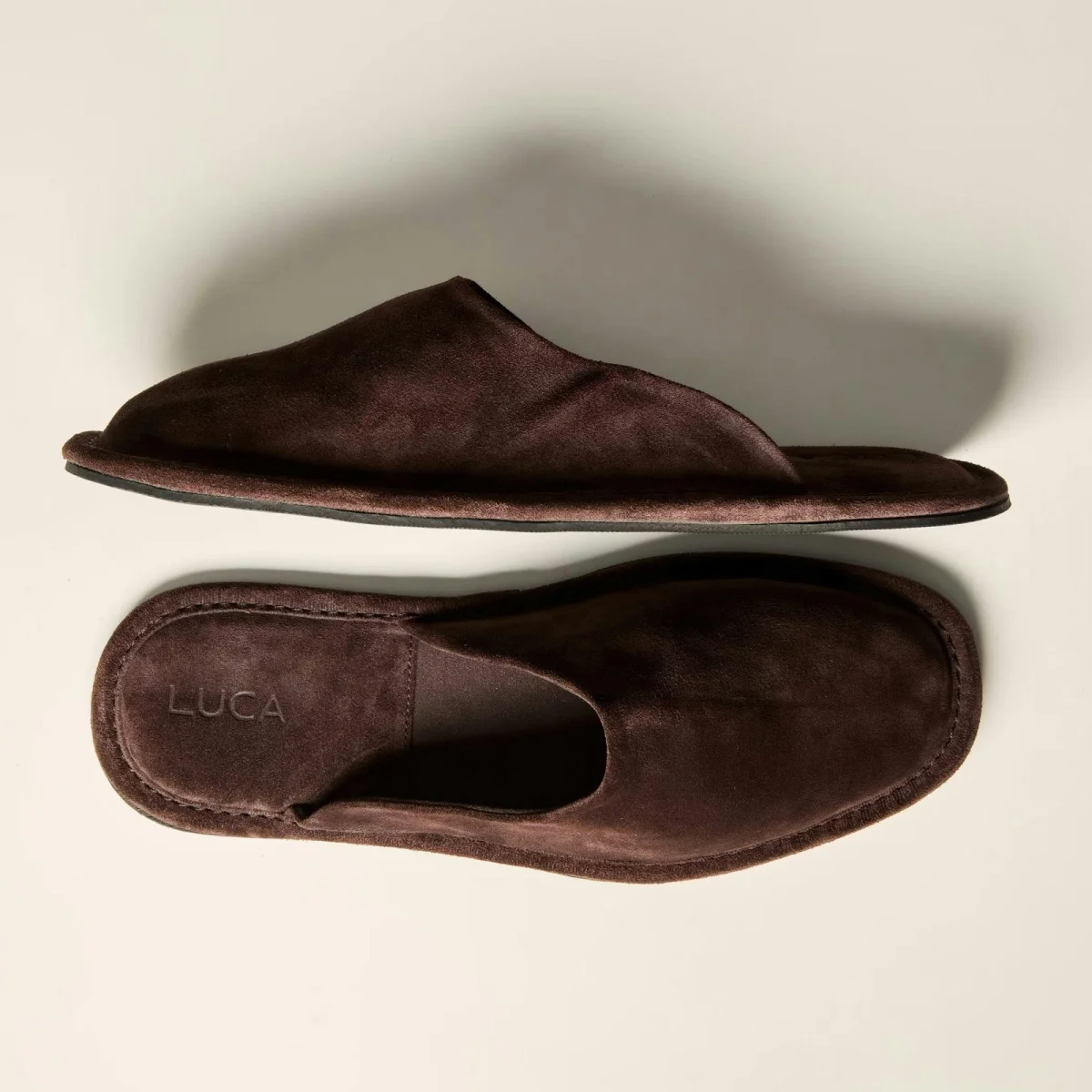 Dark brown suede slippers featuring the brand name LUCA embossed on the heel.
