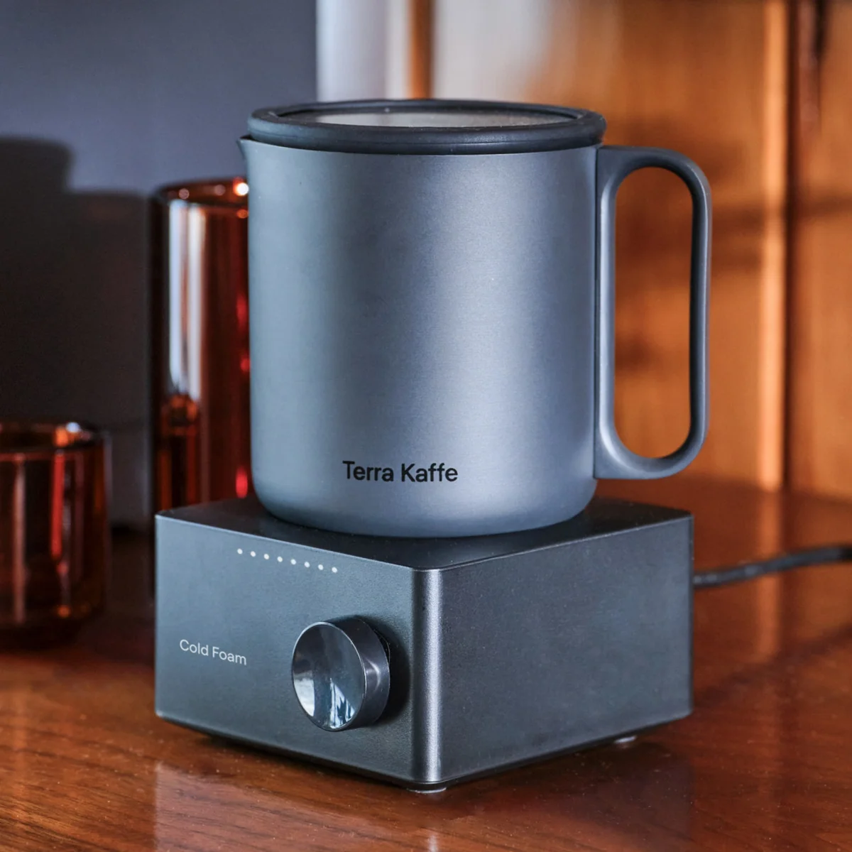 Matte gray Terra Kaffe mug with handle on top of a black Cold Foam frother with a dial knob.