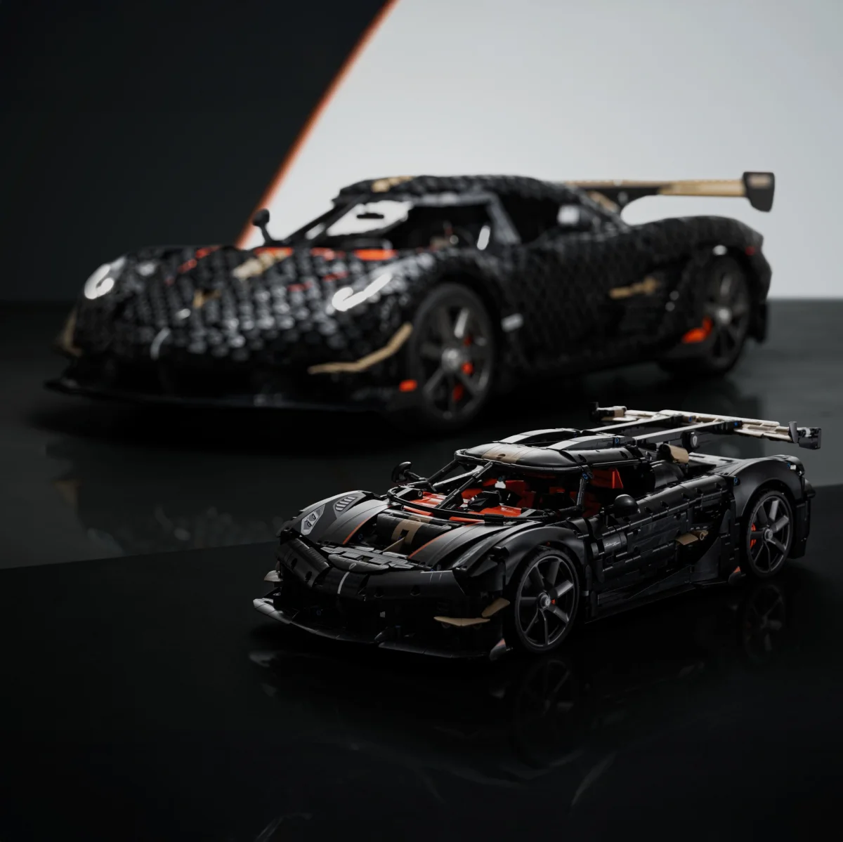 Black and tan LEGO model of a sports car with orange accents in front of a blurred similar car model.