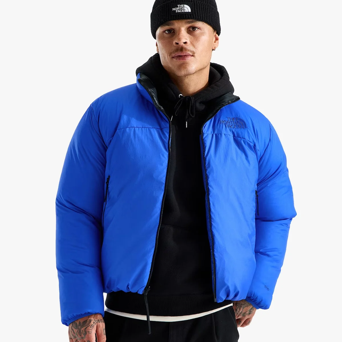 Bright blue The North Face puffer jacket worn over a black hoodie and a black beanie.