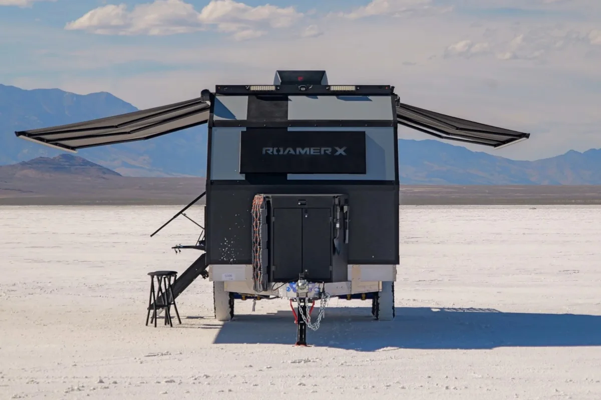 Roamer X travel trailer with two extended awnings, parked on a vast white salt flat with mountains in the background.