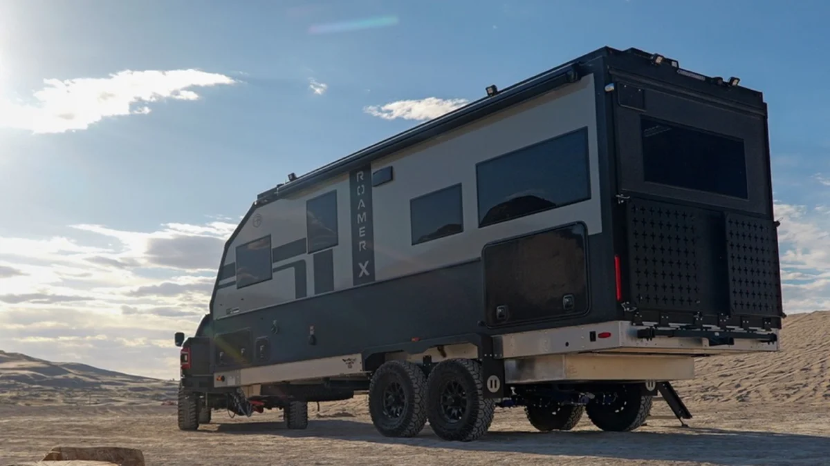 Gray and black Roamer X expedition vehicle parked on a sandy landscape.