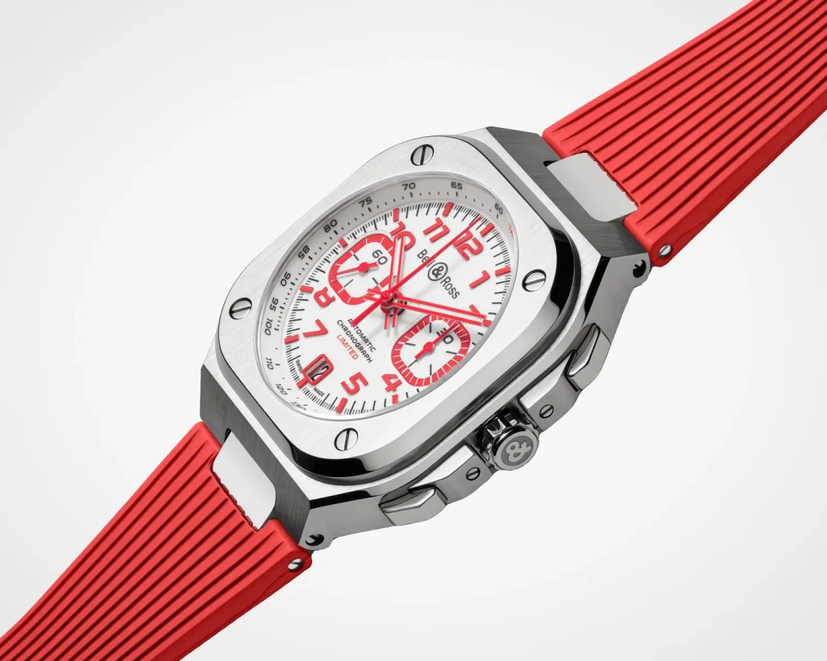 Bell & Ross automatic chronograph watch featuring a square brushed steel case, a white dial with red numerals and sub-dials, and a ribbed red rubber strap.