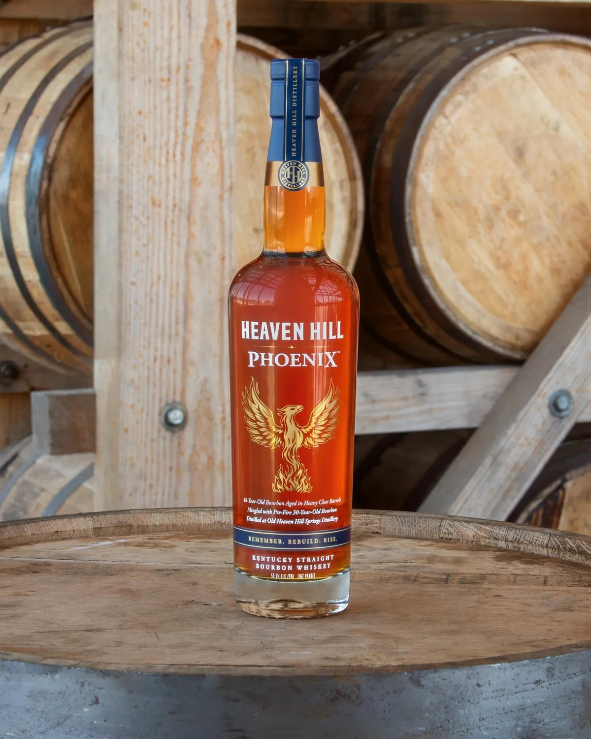 Heaven Hill Phoenix Kentucky Straight Bourbon Whiskey bottle standing upright on a wooden barrel.
