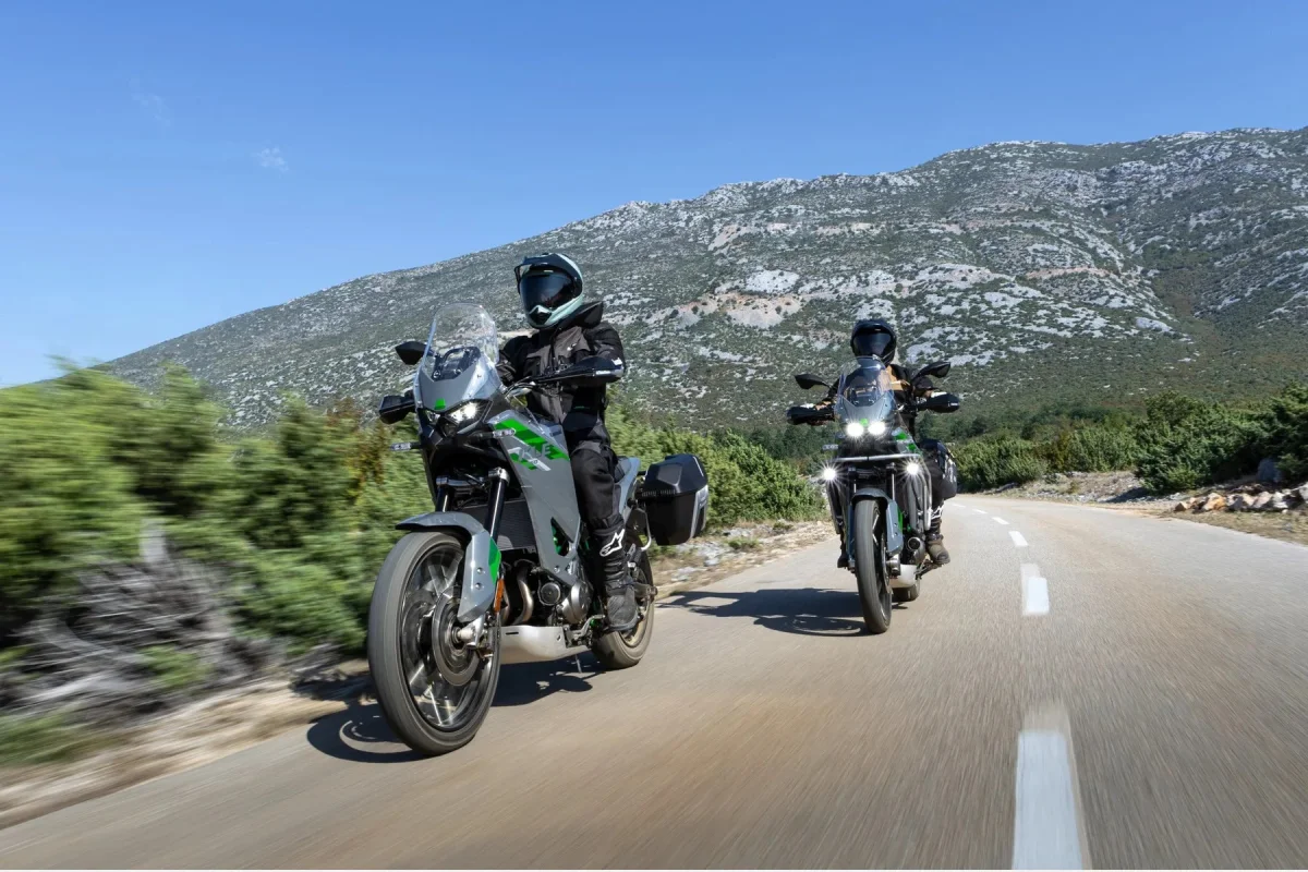 Two gray adventure motorcycles on a winding road with mountains in the background.