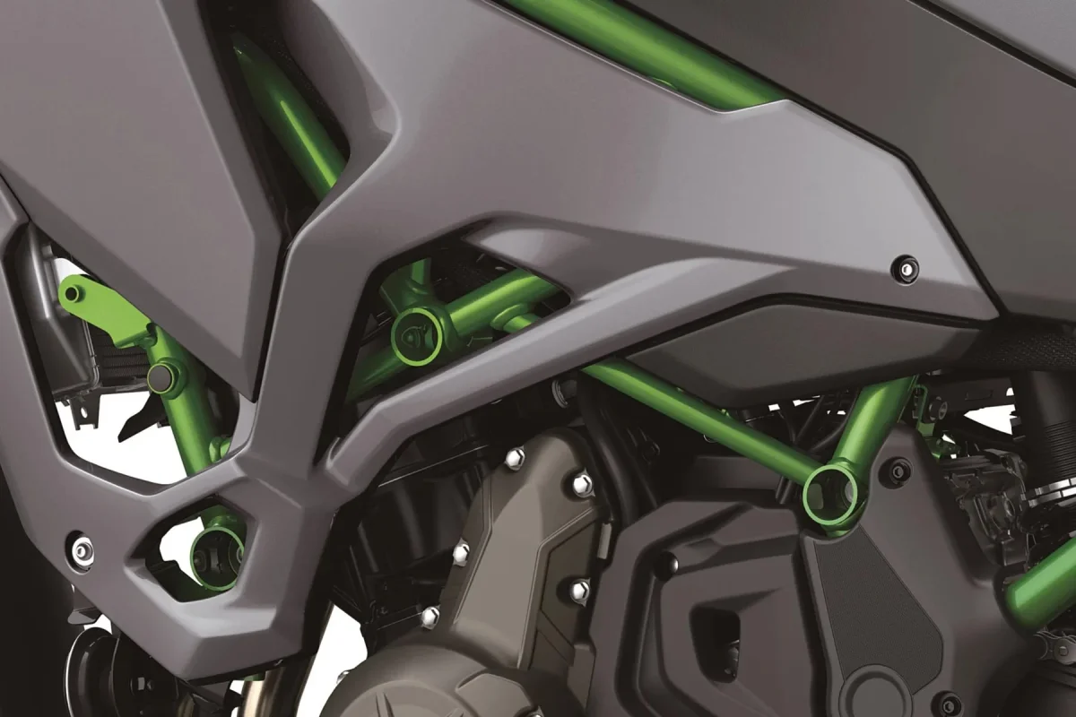 Close-up of a motorcycle engine and frame, featuring a bright green trellis-style frame against charcoal grey body panels.