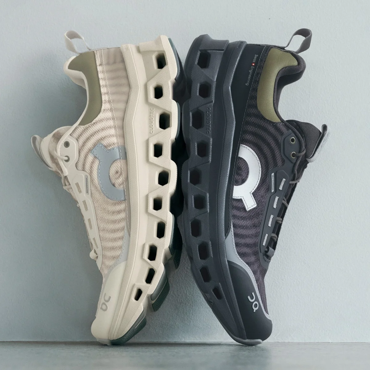 Two On running shoes in cream and black, positioned heel-to-toe with outsoles facing outward.