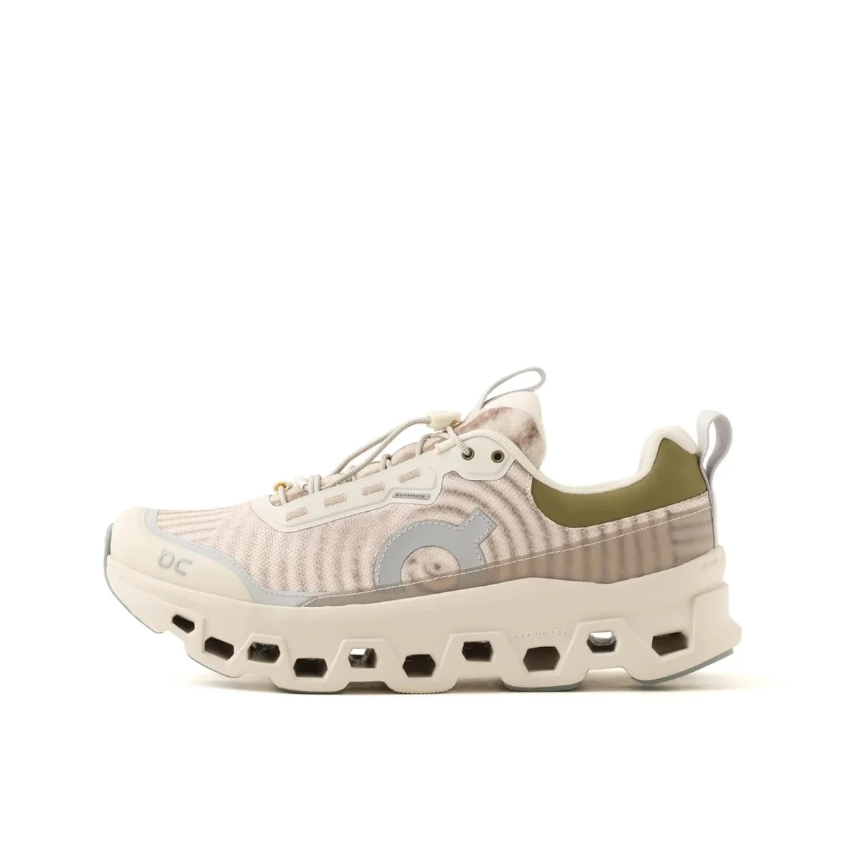 Beige On running shoe featuring a toggle lacing system, olive green collar, and a thick, lugged foam sole.