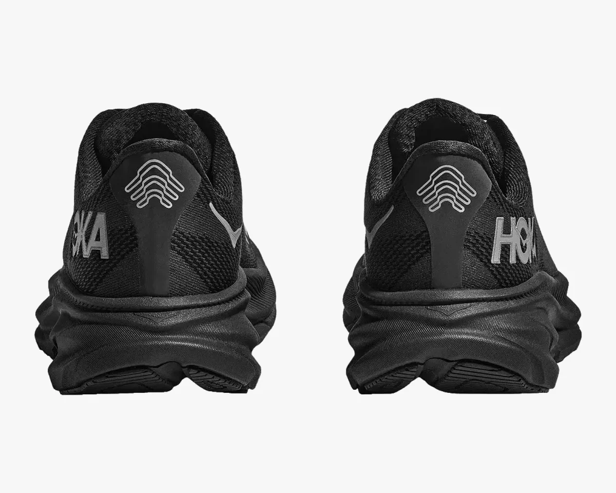 Rear view of black Hoka running shoes featuring thick midsoles and reflective brand logos on the heels.