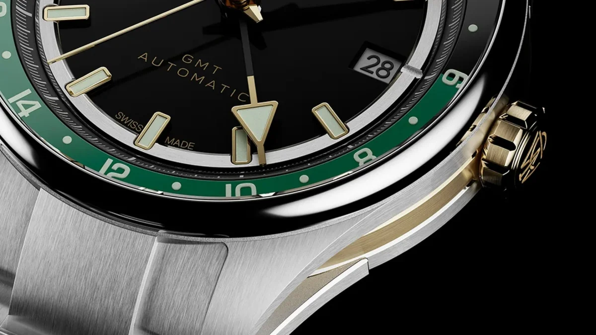 Close-up of a black GMT automatic wristwatch with green bezel, gold accents, and stainless steel case.