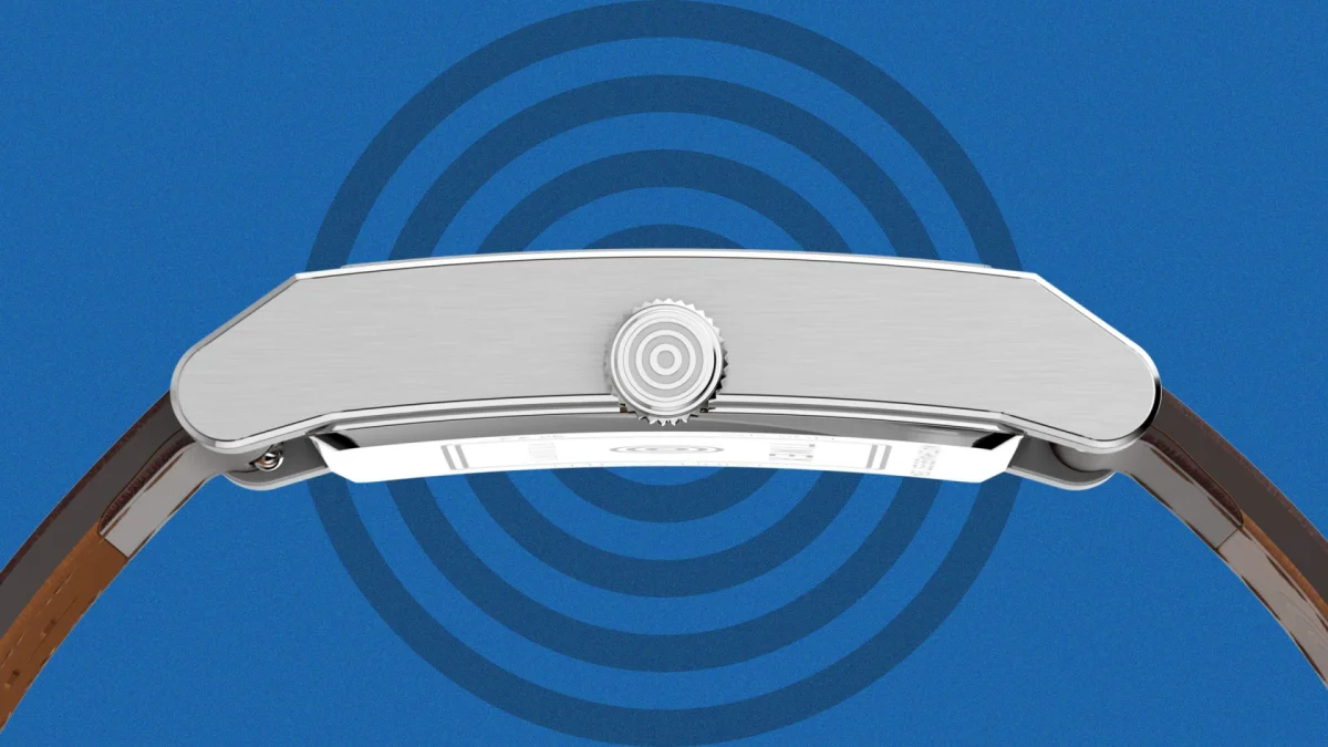 Side view of a silver-toned watch case with a textured crown and brown leather strap, set against a blue background featuring concentric circles.