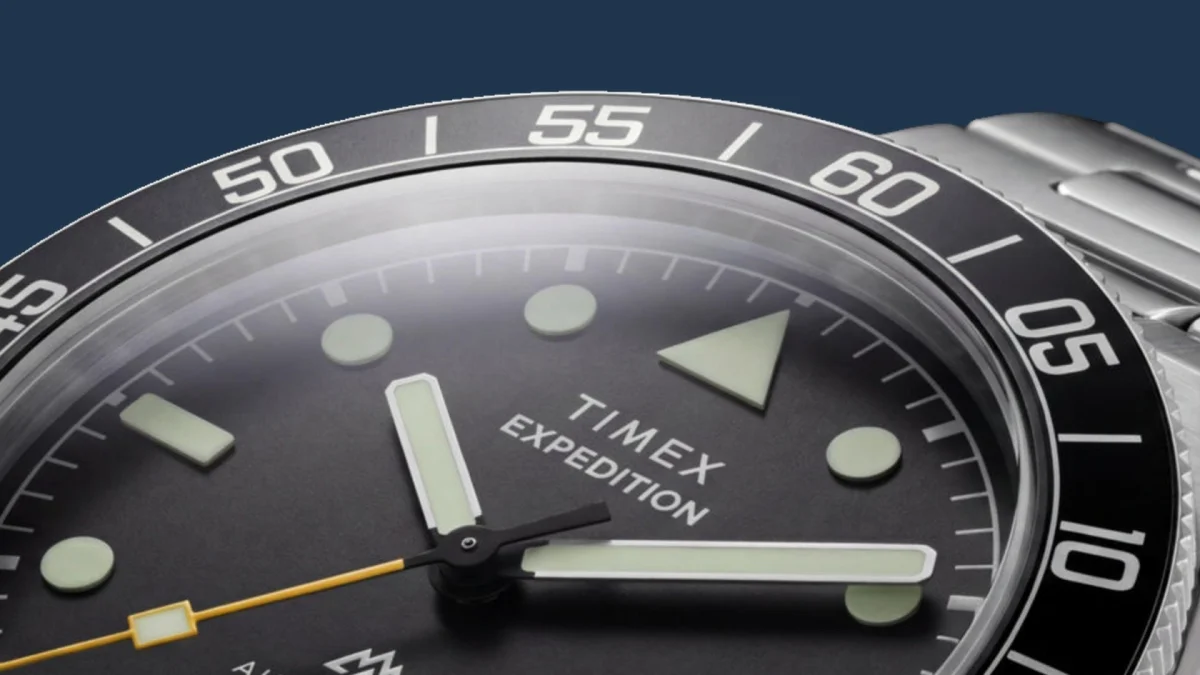 Close-up of a Timex Expedition watch face with luminous hands and markers and a black bezel with white numerals.