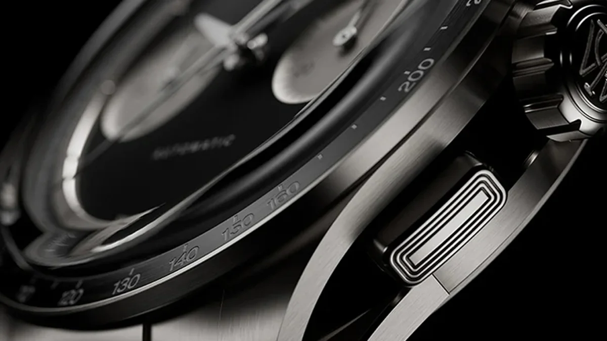 Close-up of a titanium watch bezel and side pusher with engraved tachymeter scale markings.