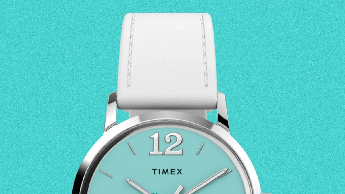 Silver Timex watch with a turquoise dial, white leather strap, and large 12 numeral at the top.