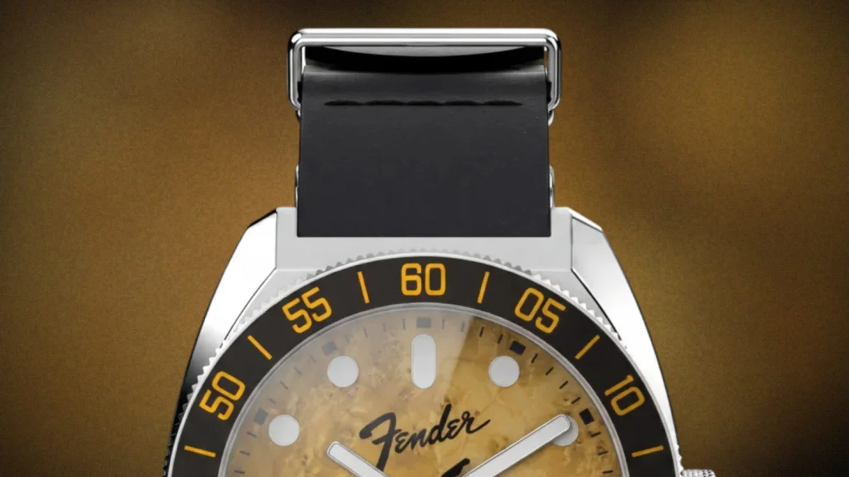 Close-up of a watch with a black strap, silver case, black bezel with yellow numbers, and a textured yellow dial with