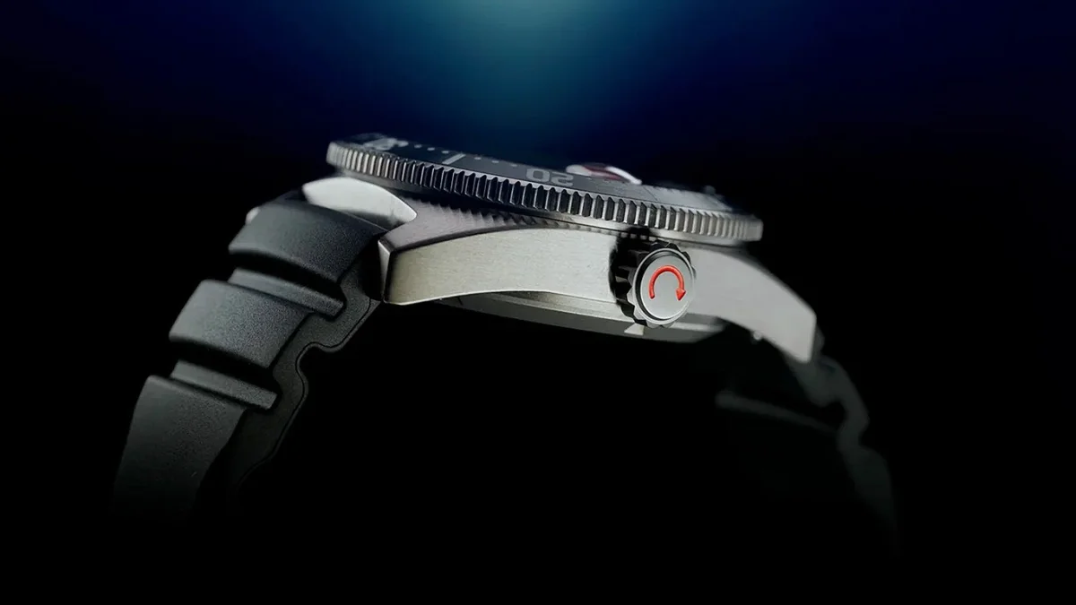 Side view of a silver metal watch case with a black rubber strap and a crown featuring a red circular arrow symbol.