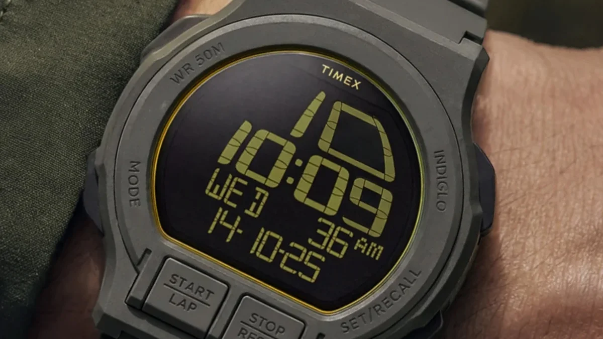 Digital Timex watch with gray case and buttons showing time 10:09 AM, date Wed 14-10-25 on a wrist.