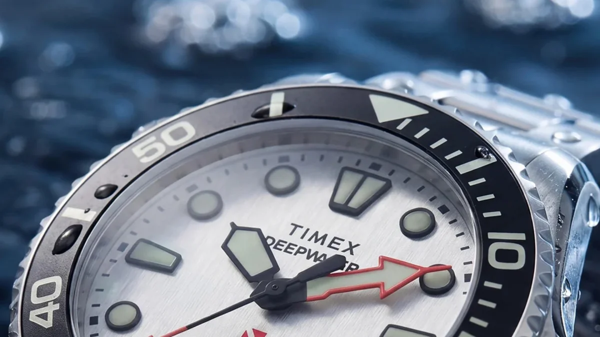 Timex Deepwater watch with silver dial, black bezel, and red arrow seconds hand.