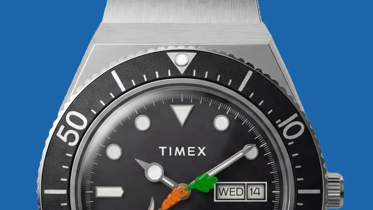Timex wristwatch with a black bezel, black dial, and white markers; day and date displayed; orange and green second hand. Blue background.